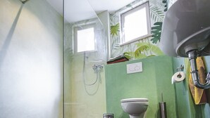 Un baño moderno con cabina de ducha de vidrio, inodoro y lavamanos.