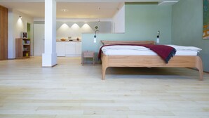 Un dormitorio amplio con una cama grande, una mesita de noche y vistas al área de la cocina.