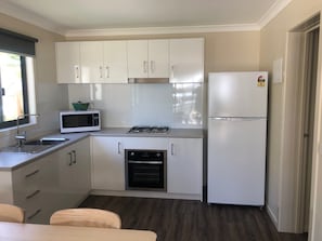 Compact kitchen with modern design, featuring a gas stove, microwave, refrigerator, sink, and oven.