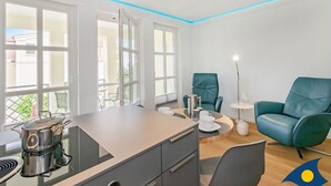 A modern kitchen with a built-in stove, a dining area with a table and chairs, and a teal armchair.