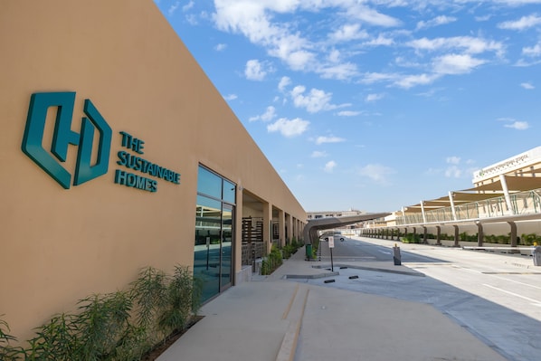 A modern building with a large logo and the words "THE SUSTAINABLE HOMES" on the facade.