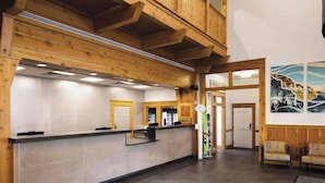 A reception area with a wooden reception desk, a balcony, and a wall with a mountain painting. - Marriott Summit Watch - Ski-In & Ski-Out - Enjoy Full Resort Access - Sleeps 8 (Park City)