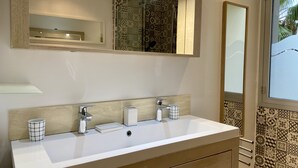 Une salle de bain dotée d’un grand miroir, de deux lavabos et de carreaux décorés.