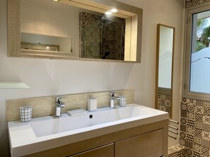 Casa de banho com um espelho grande, duas pias e azulejos estampados.