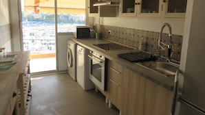 Une cuisine compacte équipée d’un lave-linge, d’un four à micro-ondes et d’un évier.