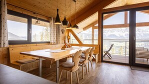A wooden interior with a large table and chairs, large windows, and a view of mountains. - Chalet with panoramic sauna (Schladming - Pichl, Ennstal)