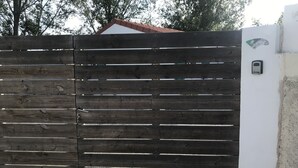 A wooden fence with horizontal slats, a metal gate, and a wall-mounted intercom.