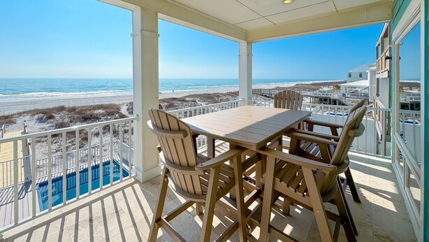 A balcony with a wooden table and chairs, overlooking a beach and ocean. - BEACHFRONT, PRIVATE HOUSE, PRIVATE POOL, PRIVATE BEACH ACCESS! (Gulf Shores)
