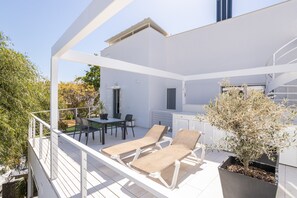 Une terrasse extérieure moderne, avec des meubles blancs, une table à manger et une plante en pot.