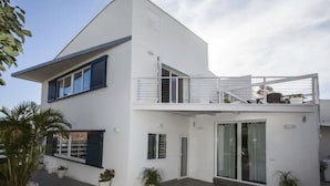 A modern two-story house with a balcony, large windows, and potted plants. - Apartment "Villa San Salvador" with Sea View, Pool, Wi-Fi & Garden (Nerja)