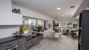 A modern kitchen with a dining area, large windows, and a view of the outside. - Apartment "Villa San Salvador" with Sea View, Pool, Wi-Fi & Garden (Nerja)