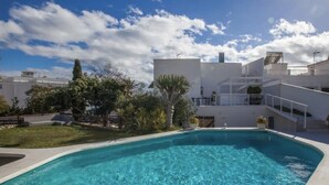 A swimming pool with clear water, surrounded by white buildings and greenery. - Apartment "Villa San Salvador" with Sea View, Pool, Wi-Fi & Garden (Nerja)
