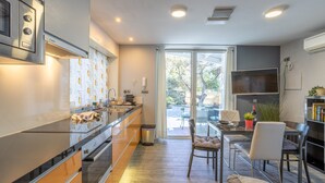 A modern kitchen with a long countertop, integrated Bosch appliances, and a dining area with a glass table and chairs.