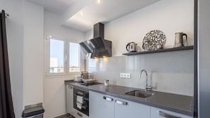 Een moderne keuken met een inbouwoven, een roestvrijstalen spoelbak en een raam met uitzicht op de stad.