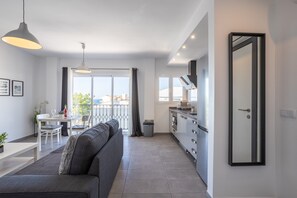 Un appartement moderne doté d’un coin repas, d’une cuisine et d’une grande fenêtre offrant une vue dégagée.