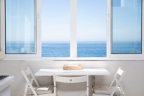 Un bureau blanc avec une plaque portant l’inscription « MARENGO », deux chaises blanches et une vue sur la mer par de grandes fenêtres.
