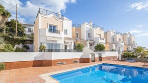 Un immeuble résidentiel doté d’une piscine, de balcons et d’une terrasse carrelée.