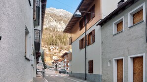 Une rue étroite bordée d’immeubles, un lampadaire et une montagne en arrière-plan.