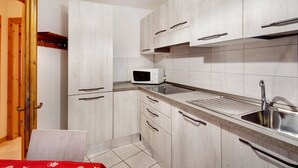 Une cuisine moderne avec des meubles en bois, un four à micro-ondes, un évier et un coin repas avec une table.