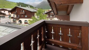 Un balcón de madera con vistas a casas tradicionales y una montaña al fondo.