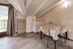 A dining area with a table set for four, a wooden cabinet, and a window with curtains.