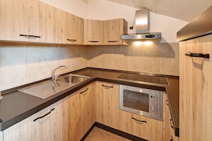 Cocina moderna con armarios de madera, pileta de acero inoxidable y microondas integrado.
