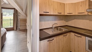 Una cocina moderna con armarios de madera, un lavamanos de acero inoxidable y vistas a un balcón.