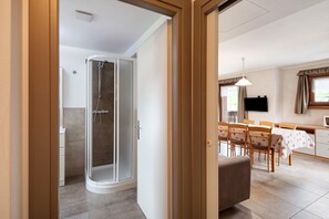 A modern interior with a shower, dining area, and kitchen.
