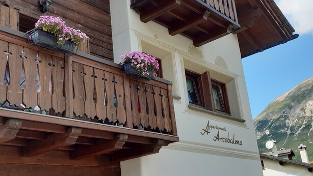 Un edificio con balcones de madera, jardineras con flores y un letrero que dice 'Aziarmenti Arcobaleno'.