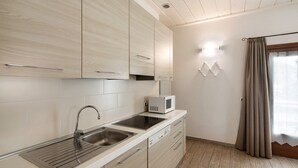 Une cuisine moderne dotée d’un évier en acier inoxydable, d’un four à micro-ondes et de meubles de rangement en bois.