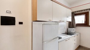 Een kleine keuken met een koelkast, magnetron en inbouwoven.