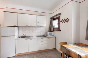 Una cucina compatta con mobili bianchi, un forno a microonde e un lavandino.