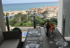 Tavolo apparecchiato per due con vista sul mare e sugli edifici sullo sfondo.