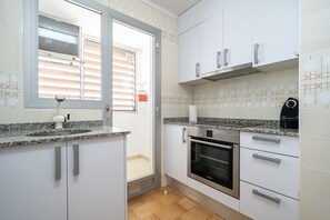 A kitchen with white cabinets, a Bosch oven, a window with blinds, and a tiled backsplash.