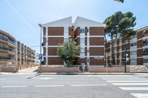 A multi-story building with a prominent entrance, a parking sign, and a crosswalk.