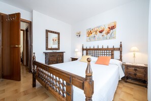 Ein Schlafzimmer mit einem hölzernen Bett, einem Nachttisch, einer Kommode, einem Spiegel und einem Bild an der Wand.