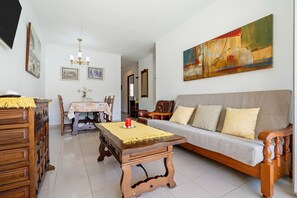 A living room with a sofa, wooden coffee table, dining table, and chairs.
