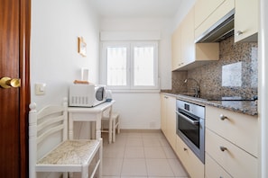 A compact kitchen with a microwave, oven, and a window.