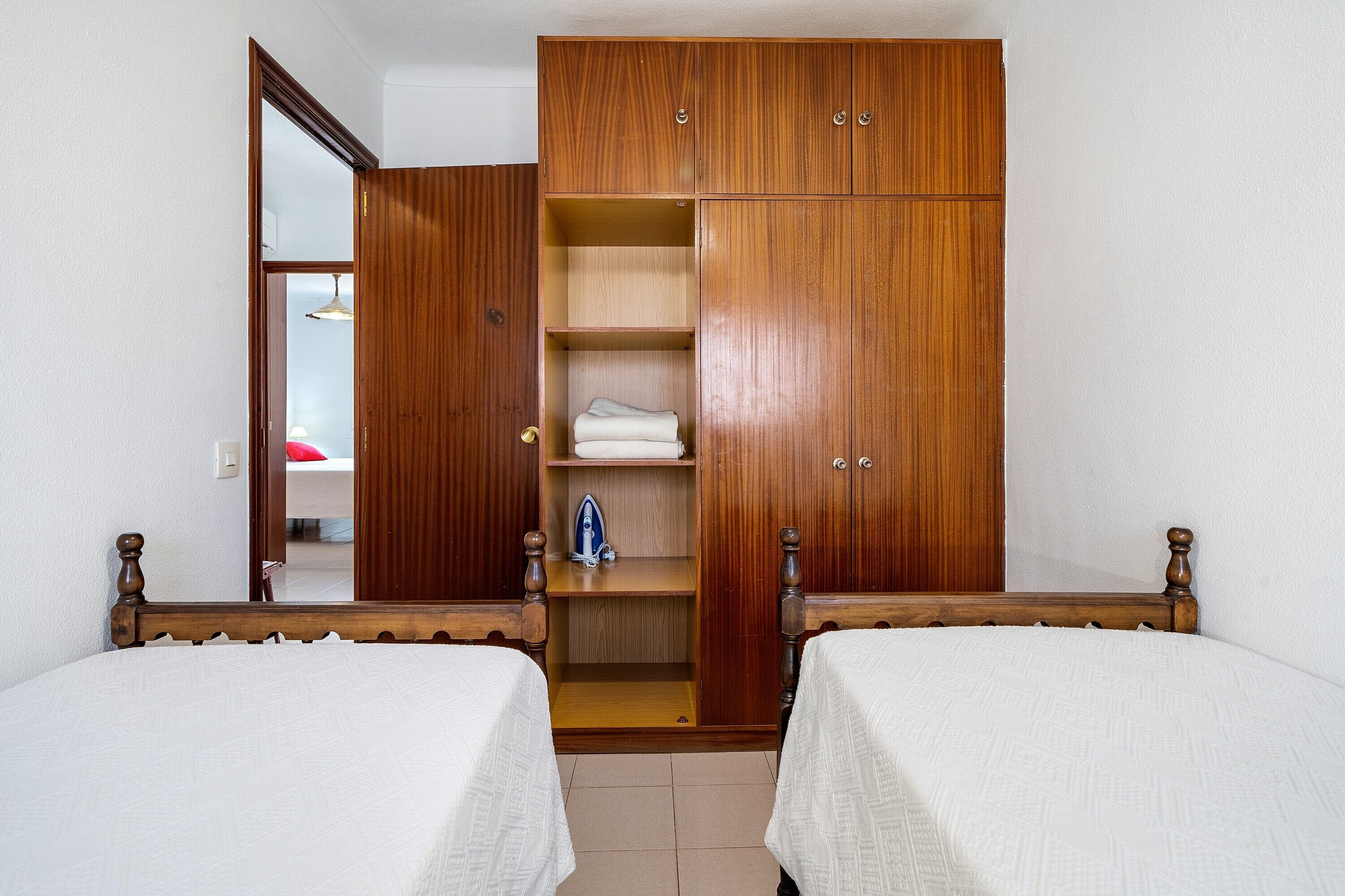 Un dormitorio con dos camas, un armario de madera y un espejo.