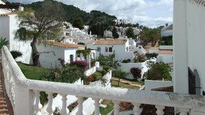 Un bâtiment blanc doté d’un balcon, entouré de verdure et d’autres bâtiments blancs.