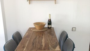 Une table à manger en bois, sur laquelle on a posé un set de table en fibres tressées, une bouteille de vin et un bol.