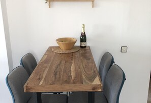 Ein Holztisch mit einer gewebten Tischmatte, einer Weinflasche und einer Schüssel.