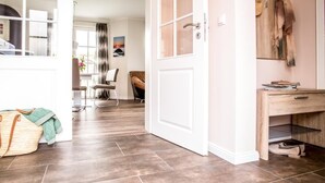 A spacious room with a large window, a wooden door, and a desk with a chair. - House Rose, luxury vacation home in Fuhlendorf for 4 people with sauna and beach chair (Fuhlendorf)