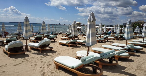 A beach with rows of sun loungers and striped umbrellas. - Seaside Apartment with 2 Bedrooms for up to 5 Guests (Sunny Beach)