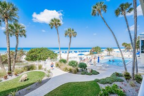 A resort with a pool, palm trees, and a beach view.