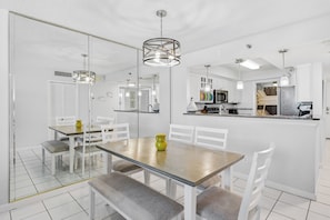 Une cuisine moderne avec des meubles blancs, un îlot central et des luminaires suspendus.