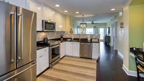 A modern kitchen with stainless steel appliances, white cabinetry, and a central island.