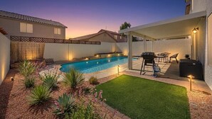 Um quintal com piscina, espaço para churrasco e um alpendre coberto.
