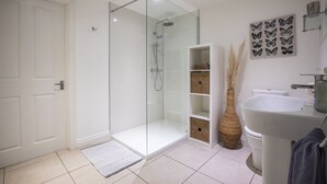 Une salle de bain moderne avec une douche à parois de verre, un lavabo blanc et un élément décoratif mural.