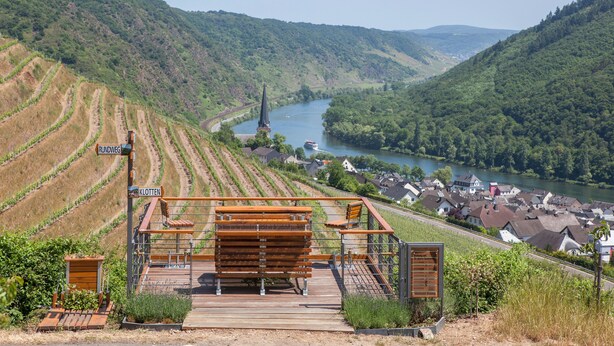 A scenic overlook with a wooden bench and a signpost indicating 'Rundweg' and 'Kloten'.